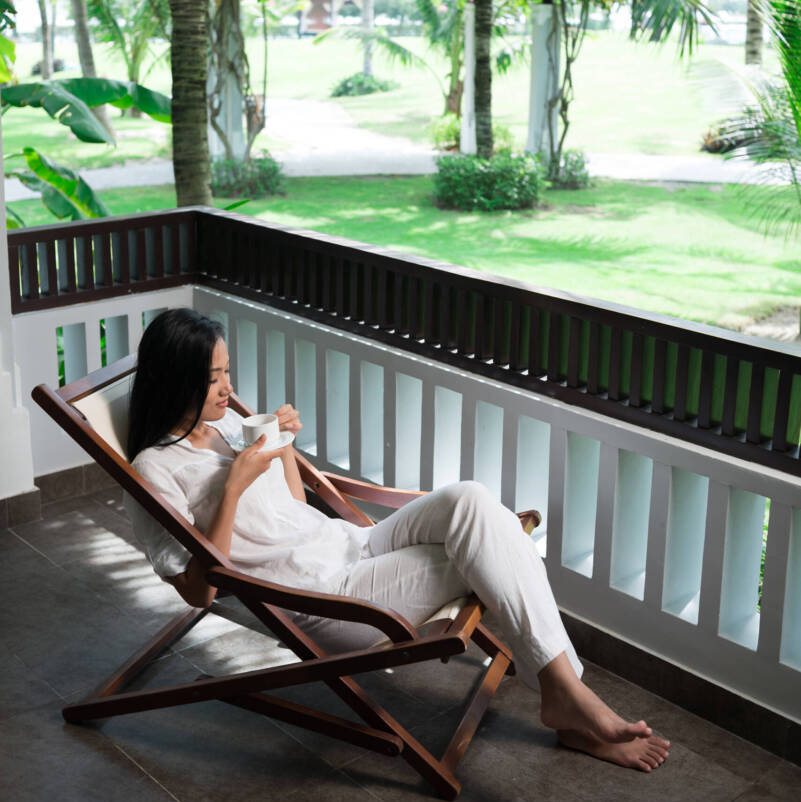 Vertical image of a serene young lady resting in the sunbed in the tranquil resort place